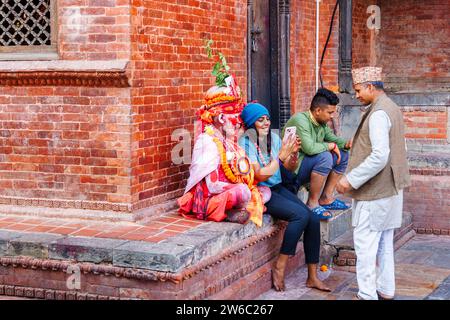 A tourist takes a selfie on her mobile phone with a local Sadhu in Pashupatinath, a UNESCO World Heritage Site in Kathmandu, capital city of Nepal Stock Photo