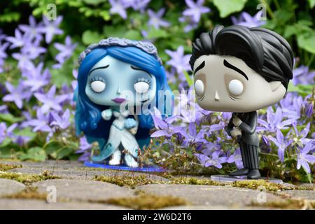 Funko Pop action figures of Emily and Victor from dark fantasy animated film Corpse Bride. Blue flowers, moss, garden, wedding, couple, romance. Stock Photo