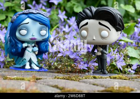 Funko Pop action figures of Emily and Victor from dark fantasy animated film Corpse Bride. Blue flowers, moss, garden, wedding, couple, romance. Stock Photo