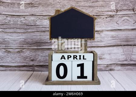 Chalkboard with April 01 calendar date on white cube block on wooden table. Stock Photo