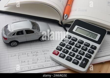 Still life illustrating the worry caused by daily life payments, a calculator next to a car and notes on tax costs Stock Photo