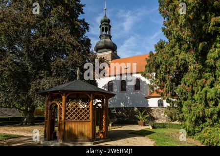 Svojsin, Czech Republic - October 13 2023: View of the Saint Petr and Pavel church with the Romanesque stone tower, a wooden summerhouse, green trees Stock Photo