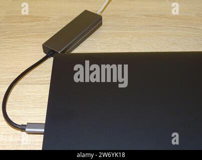 Internet cable connected to a multi-functional USB-C Hub station, Ethernet, which is connected to a laptop Stock Photo