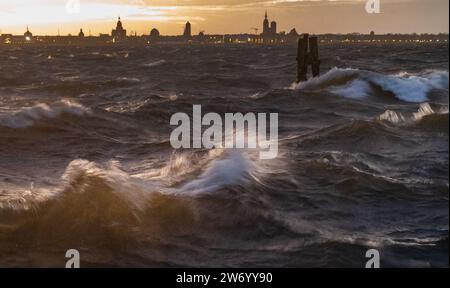 21 December 2023, Mecklenburg-Western Pomerania, Altefähr: Waves break on the beach at Altefähr on the island of Rügen. The silhouette of the Hanseatic city of Stralsund can be seen in the background. The German Weather Service (DWD) had issued a storm warning for the Baltic Sea coast from Rerik to Vorpommern due to the storm depression 'Zoltan'. There was a risk of gale-force winds from Thursday evening at 8 p.m. until Friday at noon. (to dpa 'Storm depression 'Zoltan' also disrupts the pre-Christmas period in MV') Photo: Stefan Sauer/dpa Stock Photo