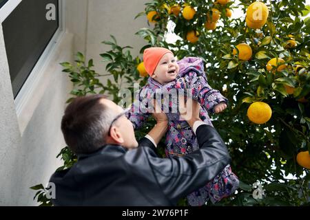 A young father lifts his little daughter above his head. Stock Photo