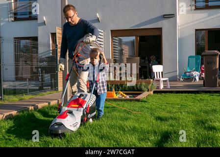 15.09.2018, Poland, Wrzesnia, Wielkopolska - Father and son mowing the lawn in the garden of their terraced house. 00A180915D223CAROEX.JPG [MODEL RELE Stock Photo
