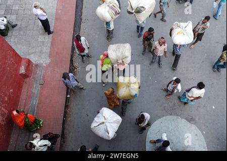 01.12.2011, India, Kolkata, Westbengalen - An everyday street scene from above shows lorry drivers with buggies on their heads between pedestrians at Stock Photo