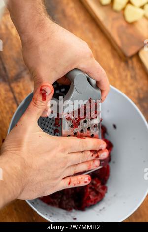 Stained hands from grating beets, kitchen activity close-up. Stock Photo