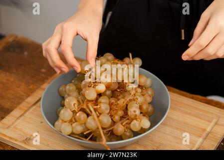 Preparing a healthy fruit platter with grapes on a chopping board. Stock Photo