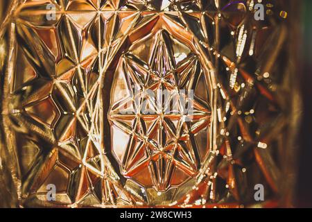 Lead diamond crystal in sunlight. Beautiful rippled glass. Glass vase illuminated with warm light. Octagram - eight-rayed star symbol macro photo. Stock Photo