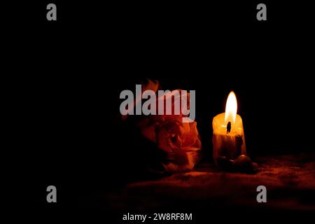 Candle flame and rose in the dark, mourning and sadness, grief for the dead Stock Photo