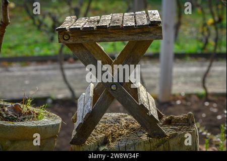 First shot of a small folding garden table, dry, old, among other utensils, tools and gardening pots, in a view of autumn, old, cold and decadent wait Stock Photo