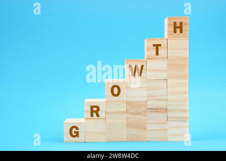 Growth word on wooden blocks staircase on blue color background. Stock Photo