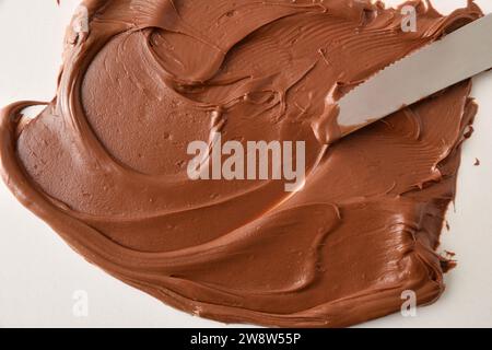 Cocoa cream spread with a knife on white background. Top view. Stock Photo