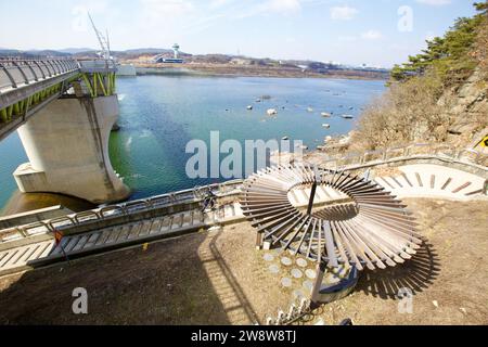 Yeoju City, South Korea - February 20, 2020: Along the Hangang Bike Path, a cyclist ascends stairs beside Gangcheon Weir, with a shaded resting area a Stock Photo