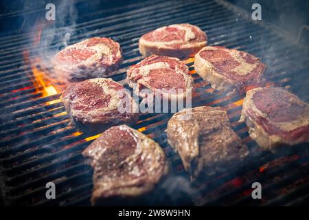 Steaks are in various stages of cooking, with some appearing more well-done than others. Stock Photo