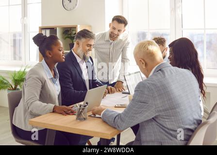 Smiling business people talking on a meeting sitting at the working place in office. Stock Photo