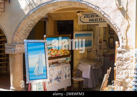 Art gallery selling framed paintings and pictures to tourists from an archway shop on Cr Masséna, facing out to covered market 'Le Marche Provencal' in Old Town Antibes, Côte d'Azur, French Riviera, France. (135) Stock Photo
