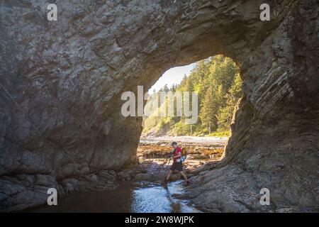 hiker enters the Hole-In-The-Wall, Olympic National Park Stock Photo