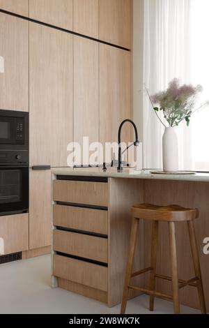 Kitchen island in a minimalist wooden kitchen with the bar chair Stock Photo