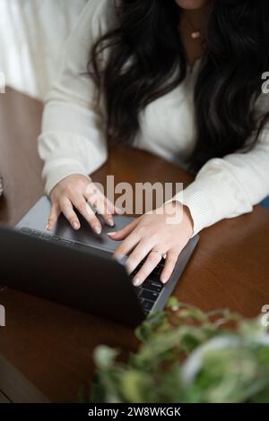 Woman working, sitting at her desk while typing on laptop Stock Photo