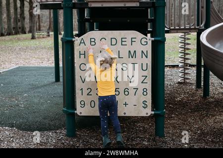 Young child playing with alphabet structure on park playground Stock Photo