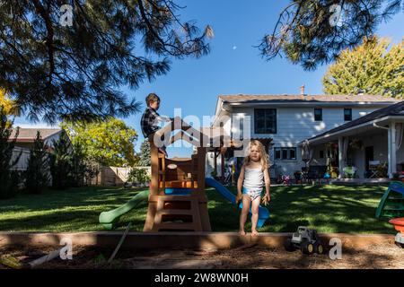 Toddler girl in diaper playing in backyard with brother Stock Photo