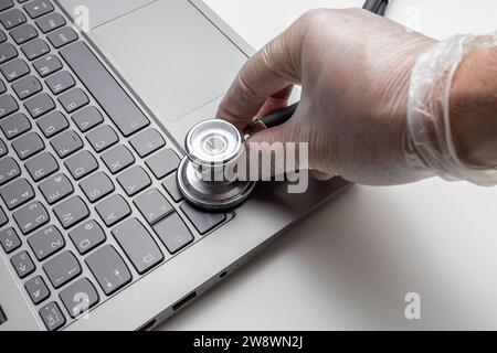 Hand with stethoscope on laptop, closeup. Concept of technical s Stock Photo