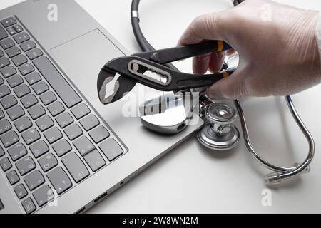 Hand with spanner and stethoscope on laptop, closeup. Concept of Stock Photo