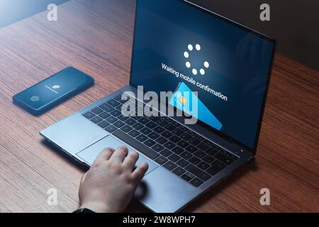 Woman use phone for online bank payment transfer on laptop. Business app. Shopping online. Digital purchase. Credit card. Stock Photo