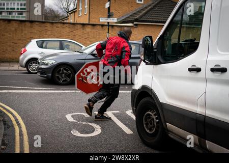 A person removes a piece of art work by Banksy, which shows what looks like three drones on a traffic stop sign, which was unveiled at the intersection of Southampton Way and Commercial Way in Peckham, south east London. Picture date: Friday December 22, 2023. Stock Photo