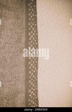 Lace curtains and their shadows. Sunlight falling on wall and creating shadow from curtains background.  Stock Photo
