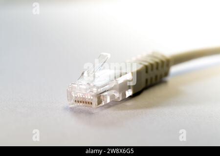Close-up macro shot of a white RJ45 Ethernet cable on a white table with copy space Stock Photo