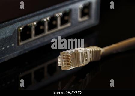 Close-up macro shot of a white RJ45 Ethernet cable on a black table with copy space Stock Photo