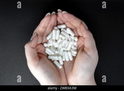 Woman hands holding pills black background Stock Photo