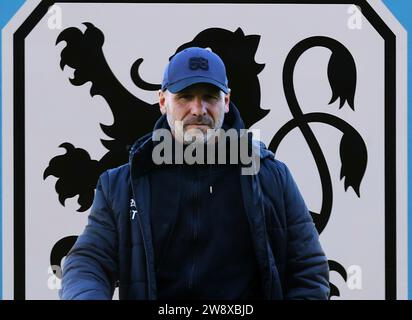 München, Deutschland 22. Dezember 2023: Fussball, Herren, 3.Liga, Saison 2023/2024, TSV 1860 München ! Achtung Fotomontage ! Hier im Bild Bernhard Trares, der von einigen als möglicher, neuer Trainer beim TSV 1860 München als Nachfolger von Jacobacci gehandelt wird, Wunschkandidat, Gerücht, im Hintergrund das Logo des Vereins Stock Photo