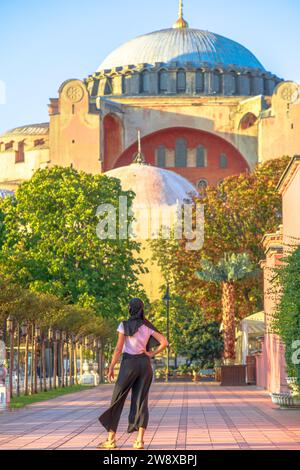 Hagia Sophia Grand Mosque, Islamic woman in Arab hijab attire admires the stunning view of Istanbul history. Magnificent monument, built by Justinian Stock Photo