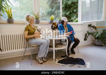 Female owners with purebred dogs waiting in animal hospital Stock Photo