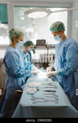 Surgical equipment arranged on table with animal surgeons in background at hospital Stock Photo