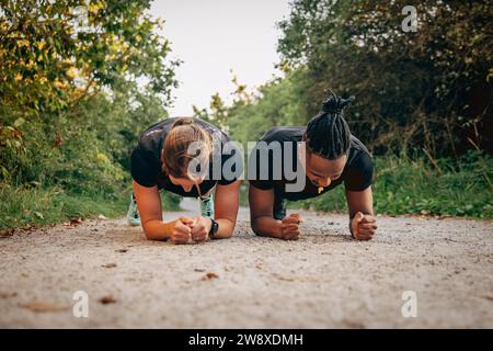Determined man and woman doing plank on footpath Stock Photo