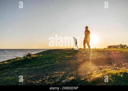 Women exercising on hill near sea at sunset Stock Photo