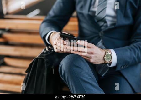Midsection of businessman using smart phone while sitting on bench Stock Photo