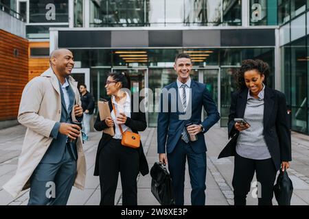 Happy male and female corporate professionals standing in front of office building Stock Photo