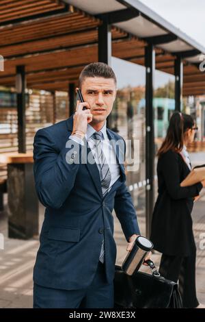 Businessman talking on smart phone while waiting at bus stop Stock Photo