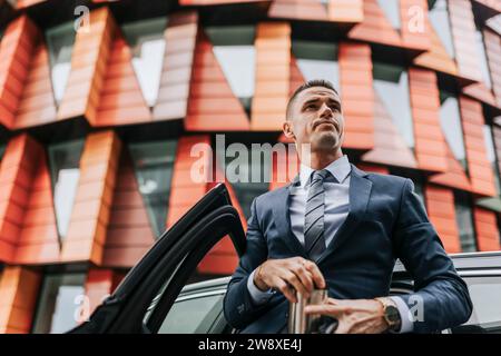 Low angle view of businessman standing near car in front of building Stock Photo