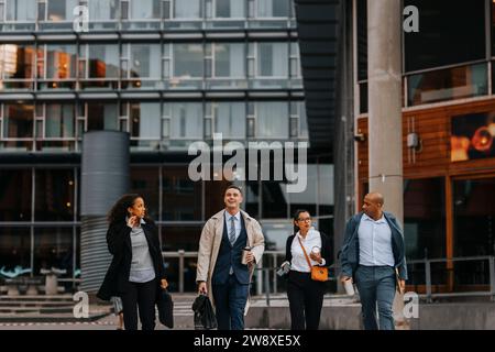 Male and female corporate professionals walking together in front of office building Stock Photo