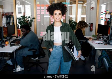 Portrait of confident female computer programmer standing with hand in pocket at office Stock Photo