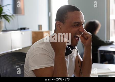 Cheerful businessman holding fist while sitting at office Stock Photo