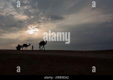 Silhouette of a camel rider amidst dramatic sunset in Sam sand dunes, Thar desert, Jaisalmer, Rajasthan, India Stock Photo