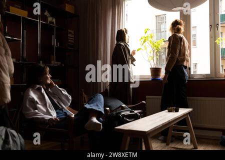 Friends looking through window with woman sitting on chair in apartment Stock Photo
